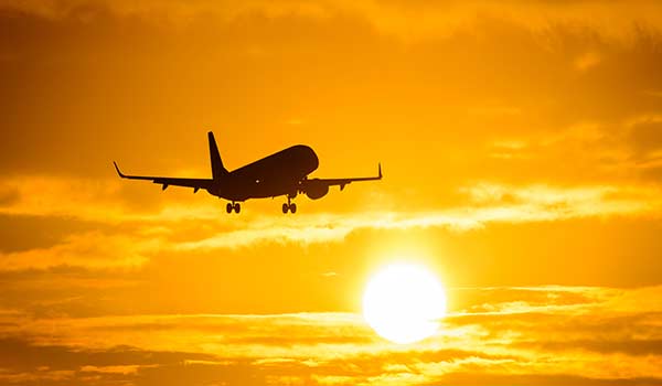 an aeroplane flying towards the sunset on a holiday to india