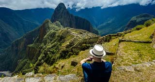 Solo traveller at machu picchu looking down onto the ruins, one of the many stops for this tourist on a  travel world tour