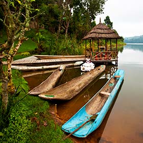 lakes and small traditional boats in Uganda next to green vegetation