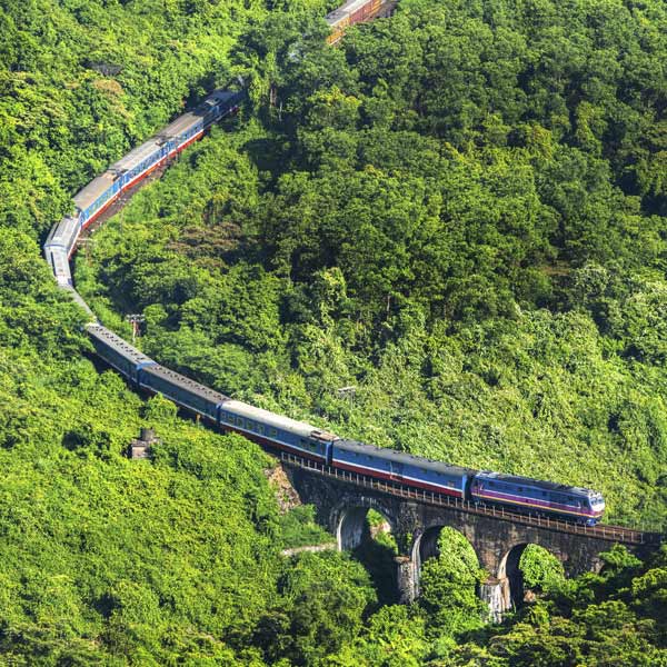 Holiday maker takes a photo of a train carrying passengers through the Hai Van Pass near Hue, Vietnam