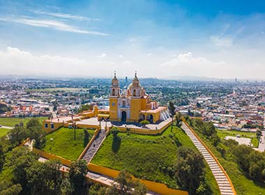 church on topof a hill looking down into the city of puebla in mexico