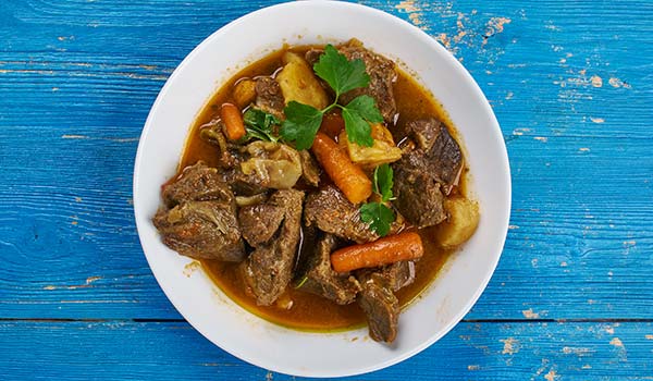 cape malay curry with vegetables on blue wooden table