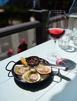 oysters in a black dish with a glass of wine on a white table for the knysna oyster festival