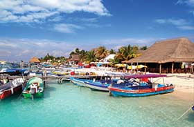 Fishing boats on the beach and turqoise sea with wooden huts on the beach in Mexico